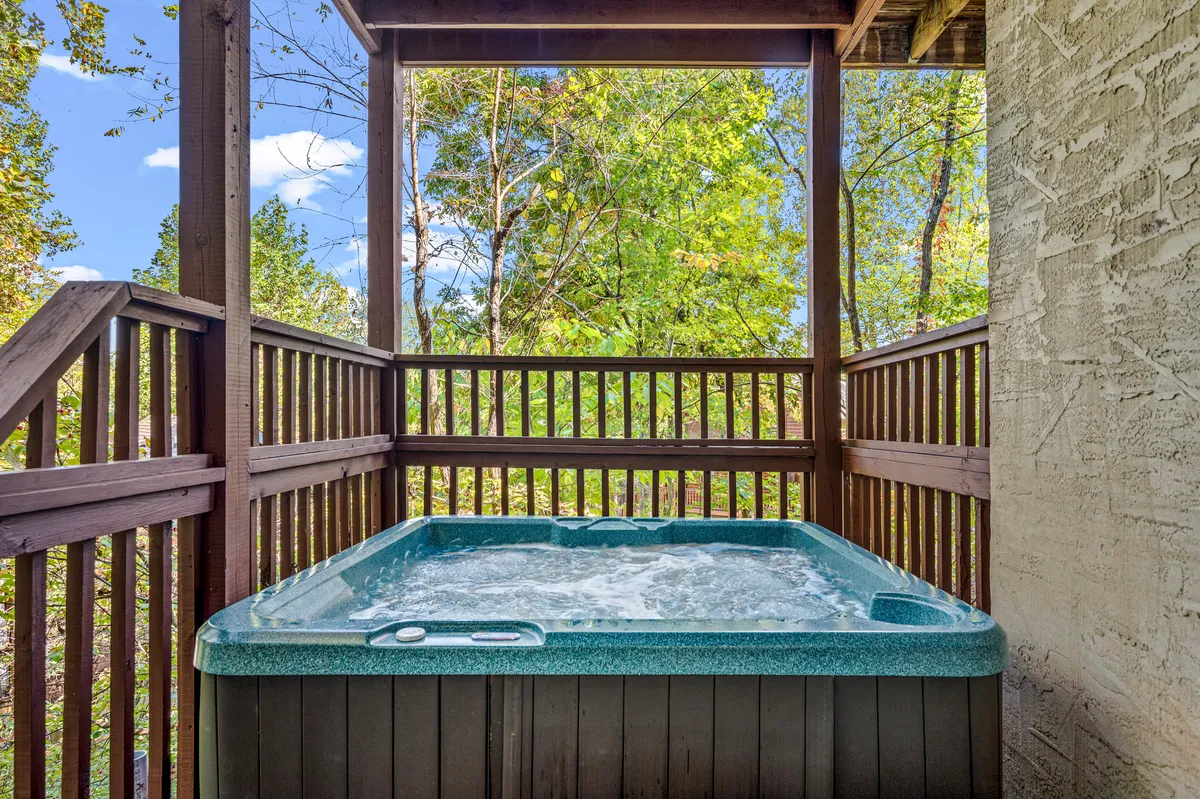 A peaceful hot tub sits outdoors, bordered by lush greenery. The setting is secluded, perfect for unwinding after an active day or for evening conversations under the stars. The inviting water and natural surroundings make it ideal for relaxation and shared moments.